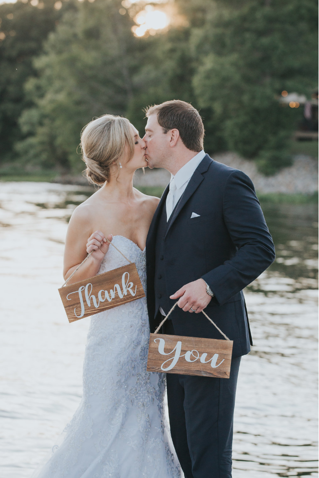 Bride and groom holding a thank you sign next to the lake